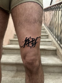 a man with a tattoo of arabic calligraphy on his leg