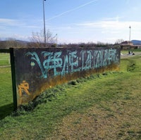 a sign with graffiti on it next to a grassy field