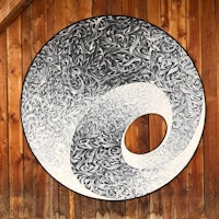 a black and white yin yang painting on a wooden wall